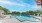 a swimming pool with a deck and chairs and trees in the background